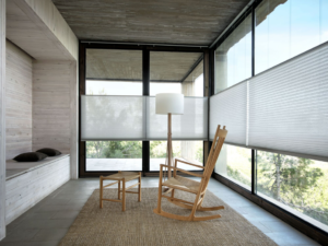 Room with large windows, white blinds and wooden rocking chair. 